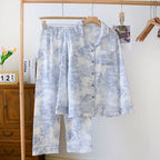 Floral patterned shirt and pants set hanging on a rack with a wooden cabinet and books in the background.