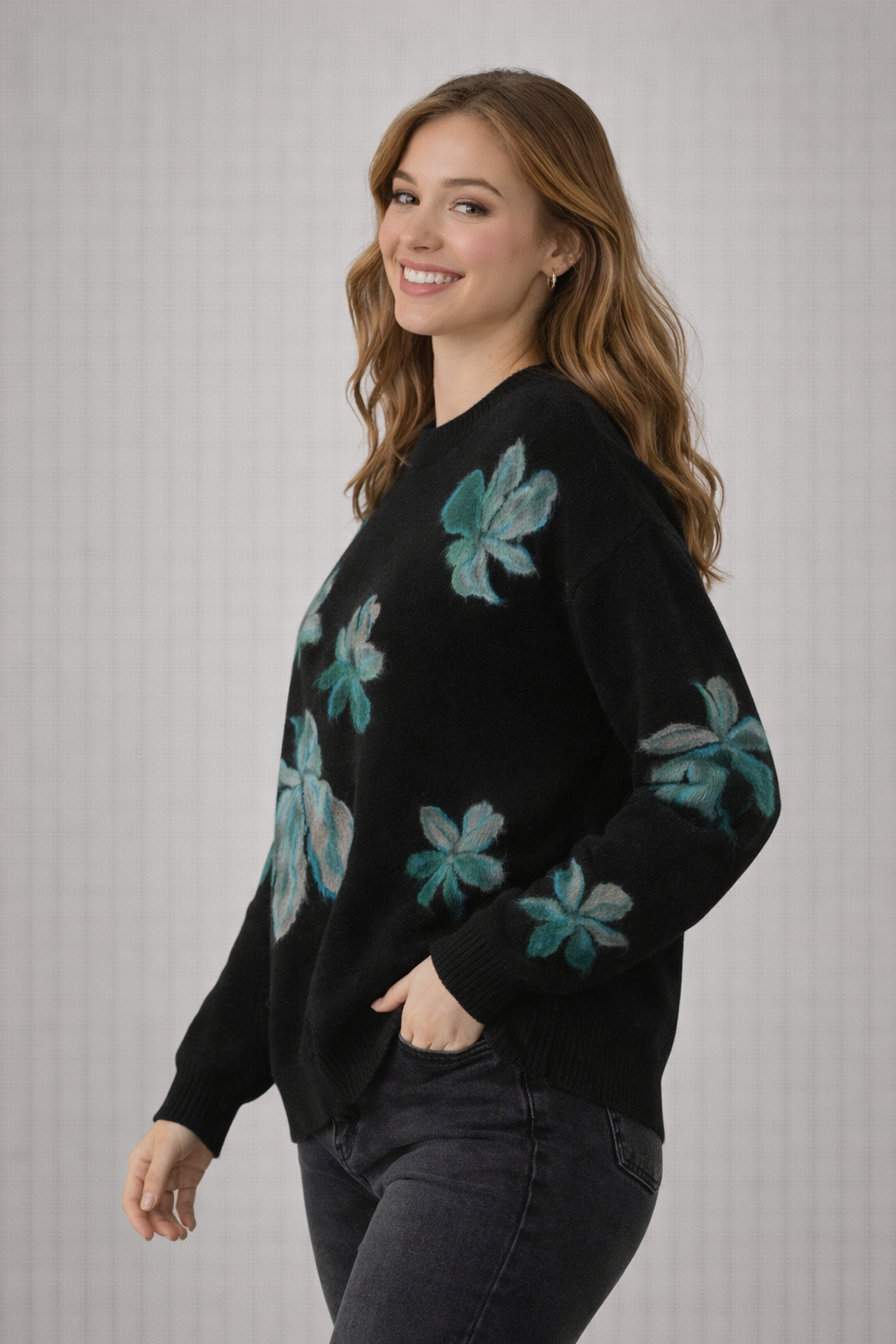 Woman wearing a black sweater with teal floral patterns on a gray background