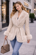 Person wearing a beige fur coat taking a walk in the city
