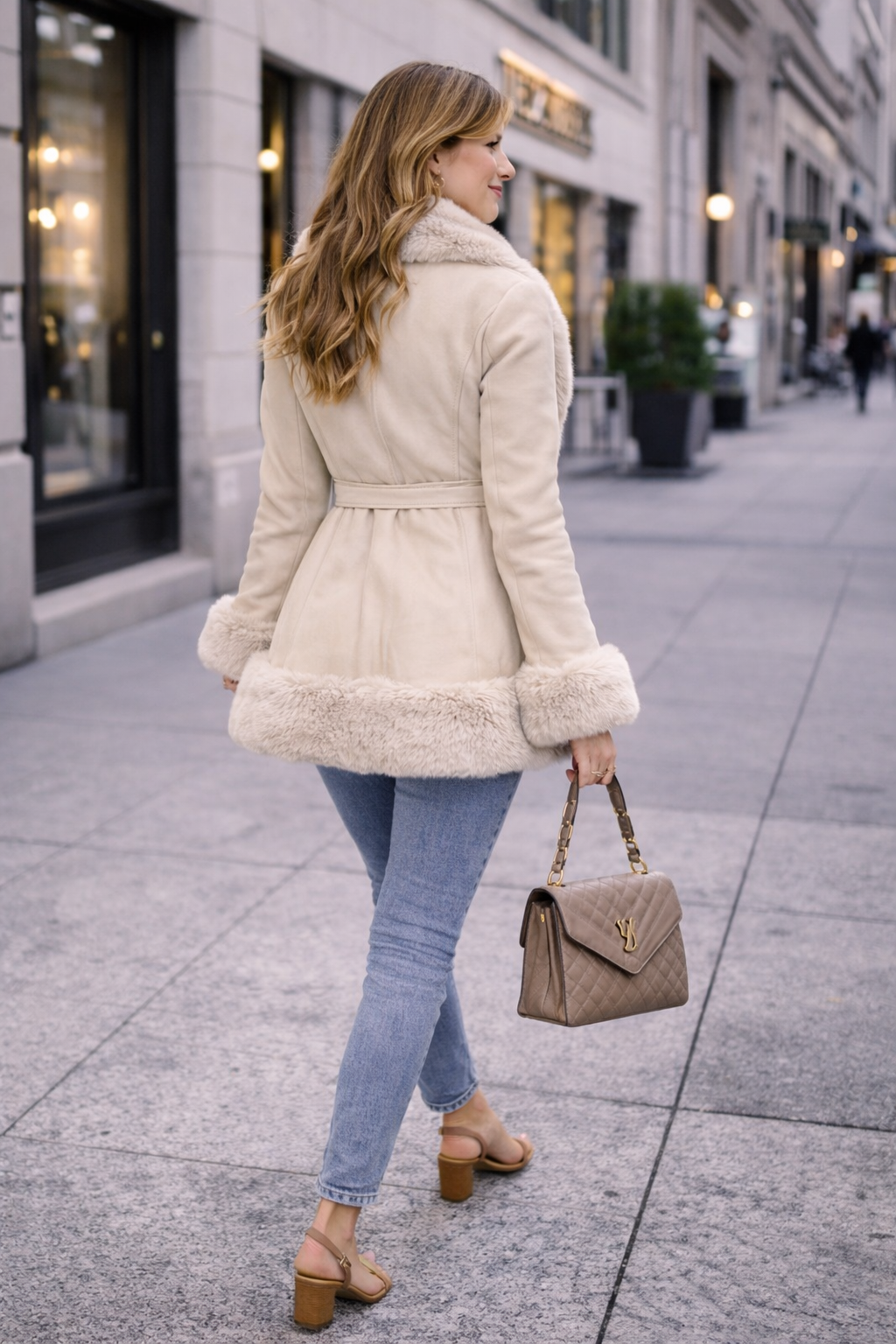 Person wearing a beige fur coat taking a walk in the city