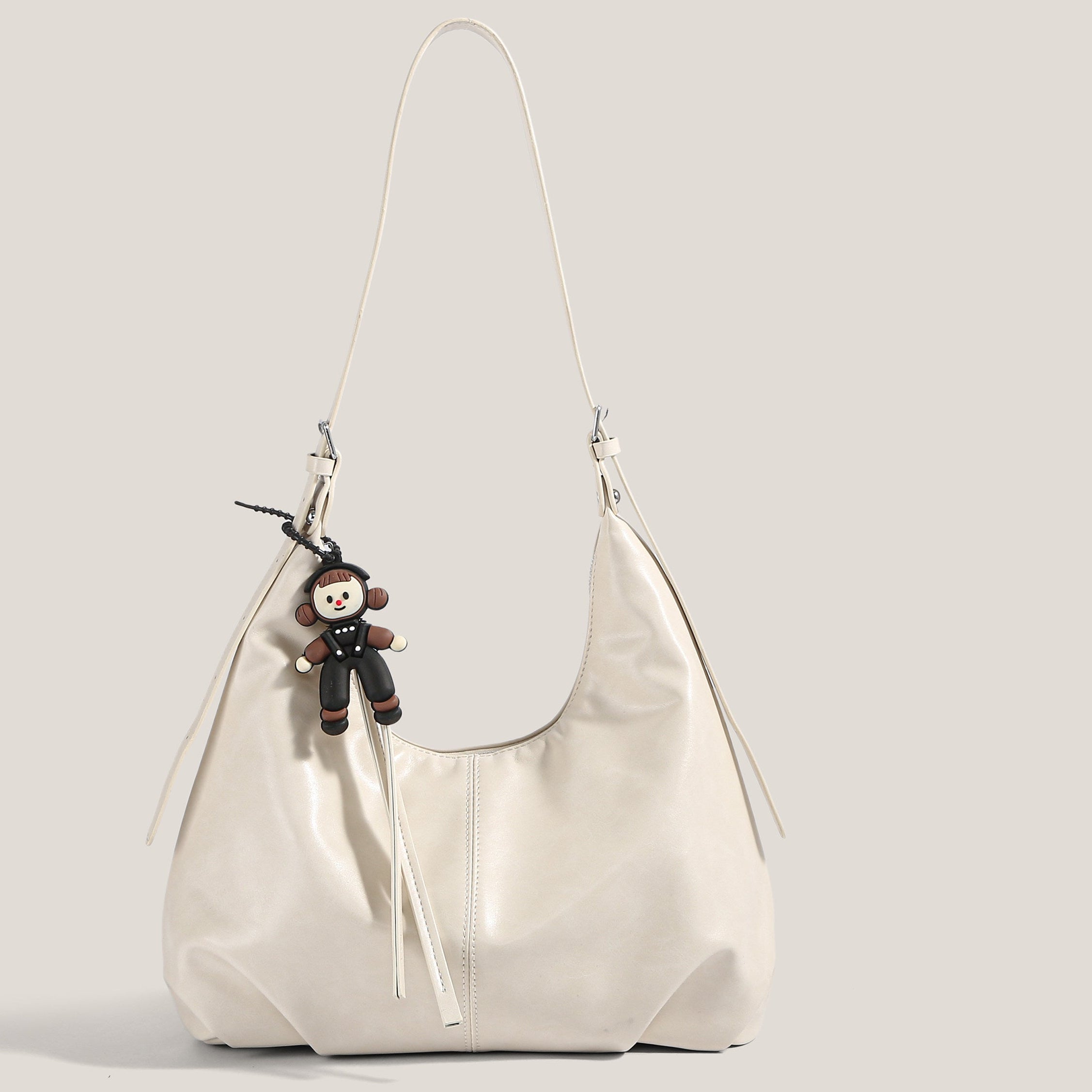 White handbag with a small black monkey charm on a light gray background, featuring the King Studio brand.