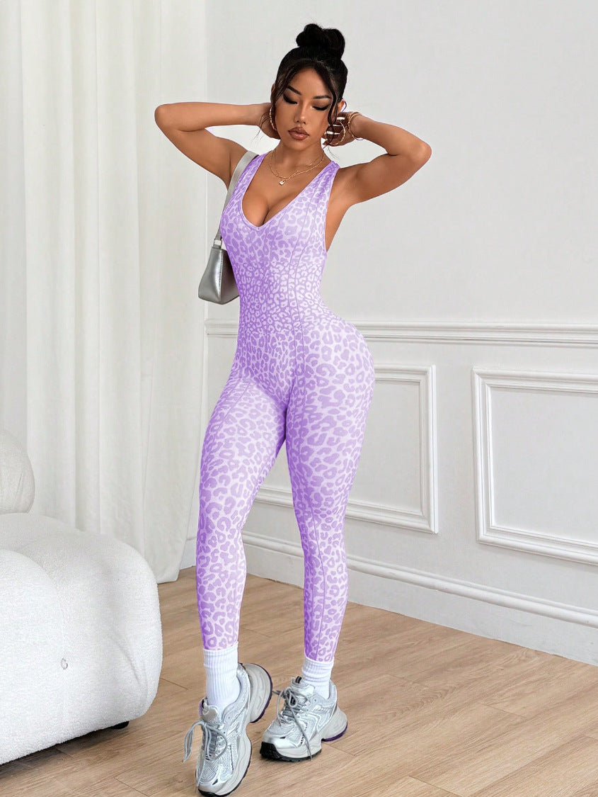 Woman wearing a purple leopard print jumpsuit in a room with white walls and wooden floor.