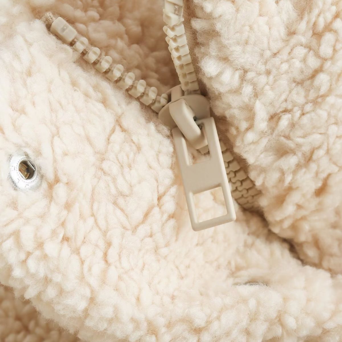 Close-up of a beige zipper on a textured fabric background