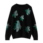 Black sweater with green floral patterns on a white background